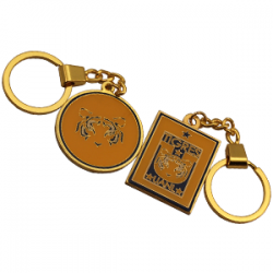  Two gold keychains: one round with a stylized tiger face and one rectangular with a "Tigres" logo and stars. 