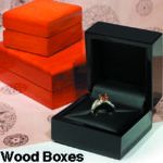  A black jewelry box containing a ring with an orange gemstone is in the foreground. Behind it are stacked orange wooden boxes. Text at the bottom reads "Wood Boxes. 